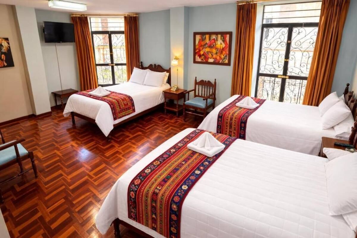 A hotel room with two beds, a TV, a desk, and a chair.