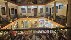 A multi-level atrium with a central glass floor, balconies with railings, and potted plants. - Hostal Viena Internacional (Quito)