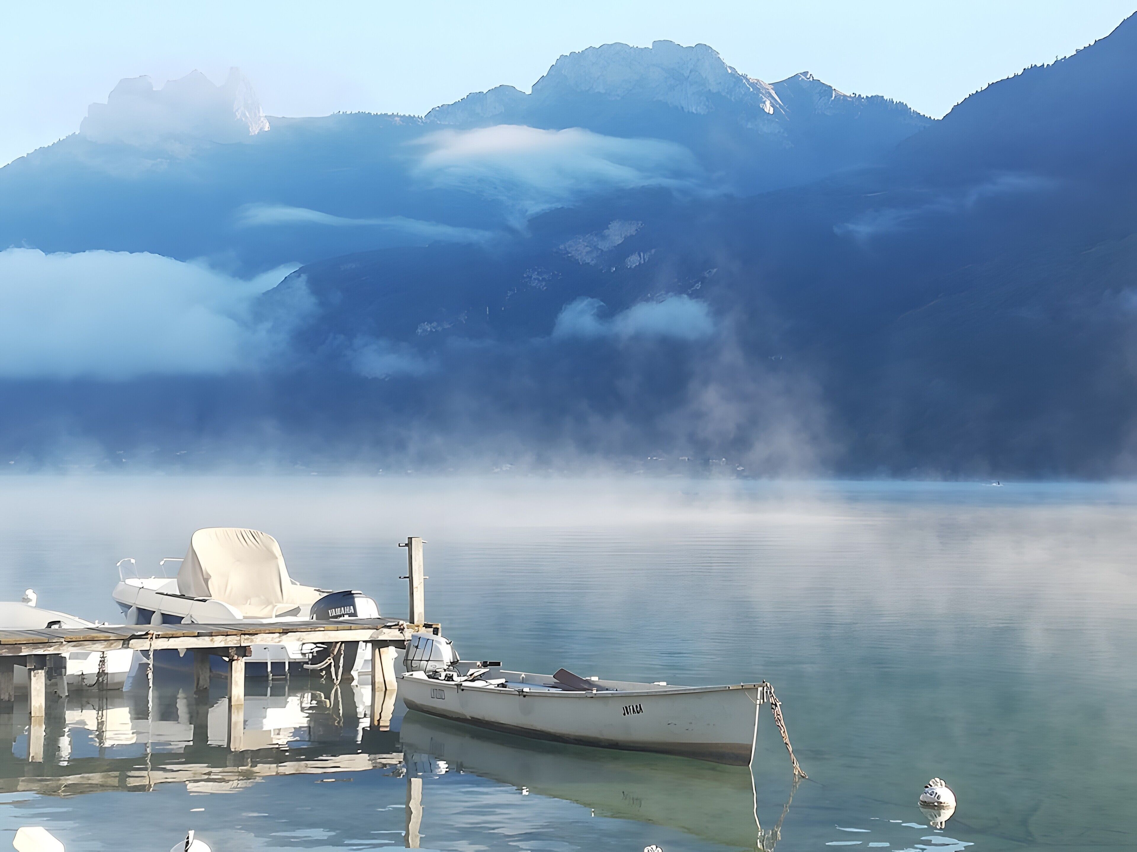 Un barco amarrado en un muelle con montañas al fondo.