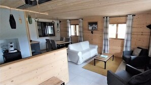 Ein Holzinterieur mit einer Couch, Stühlen, einem Esstisch und einem Fernseher.