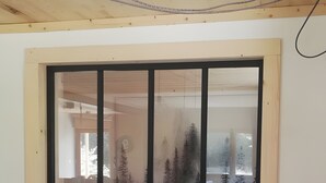 Ein Zimmer mit großem Fenster und Blick auf ein bewaldetes Gebiet.