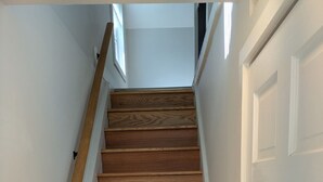 Eine Holztreppe mit weißen Wänden und einer weißen Tür.