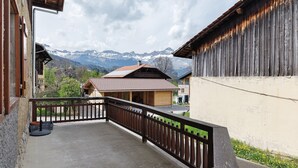 A balcony with a view of mountains, a wooden fence, and a building with a sloped roof. - Bed and Breakfast 'La Ferme Du Mont Blanc - Vallot' with Mountain View (Combloux)