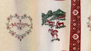 A fabric with embroidered designs including a heart with the word 'Montagne,' a mountain scene, and animals. - Bed and Breakfast 'La Ferme Du Mont Blanc - Gouter' with Mountain View and Wi-Fi (Combloux)