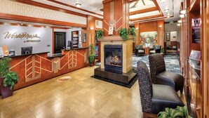 A lobby with a reception desk, a fireplace, seating area, and a view of the outside. - San Diego | City Escape | Sun Deck + Fitness (San Diego)