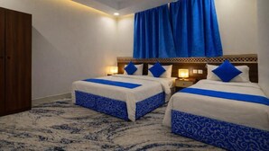 Habitación de hotel con dos camas, un armario de madera y una alfombra estampada.