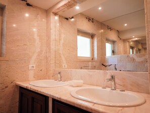 Ein Badezimmer mit zwei Waschbecken, einem großen Spiegel und Marmorwänden.