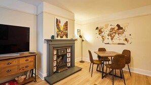 A living room with a fireplace, a dining table with chairs, a flat-screen TV, and a world map on the wall. - Host & Stay | Bridge Court (Yarm)