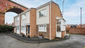 A two-story residential building with a brick facade, a small front garden, and a visible archway in the background. - Host & Stay | Bridge Court (Yarm)
