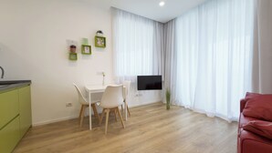 Un salon moderne comprenant un coin repas, un téléviseur à écran plat fixé au mur et un canapé rouge.