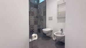 Ein modernes Badezimmer mit Duschkabine, Toilette, Bidet und Waschbecken.