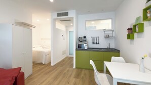 Une chambre d’hôtel compacte comprenant un coin cuisine, un lit et un espace repas.