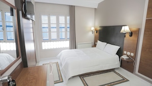 Una camera d'albergo con un letto, un comodino, una lampada e un grande specchio.