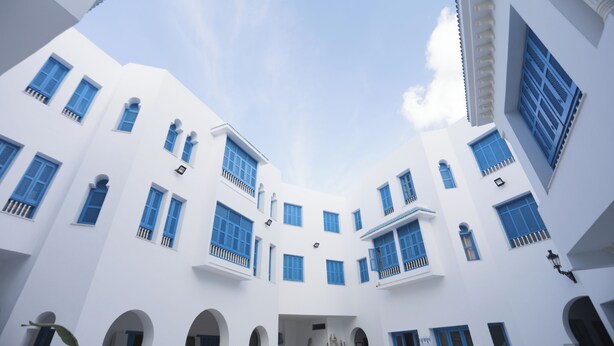 Un edificio bianco con numerose finestre e balconi, caratterizzato da un cortile centrale.