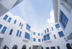Ein weißes Gebäude mit zahlreichen Fenstern und Balkonen, das einen zentralen Innenhof beherbergt.