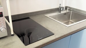 A kitchen with a black induction cooktop, a stainless steel sink, and a control panel. - Villa Ada-Nicola - One Bedroom Apartment, Sleeps 2 (Olbia)