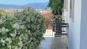 A balcony with a tiled floor, a metal chair, and a white wall. - Villa Ada-Orazio - One Bedroom Apartment, Sleeps 2 (Olbia)