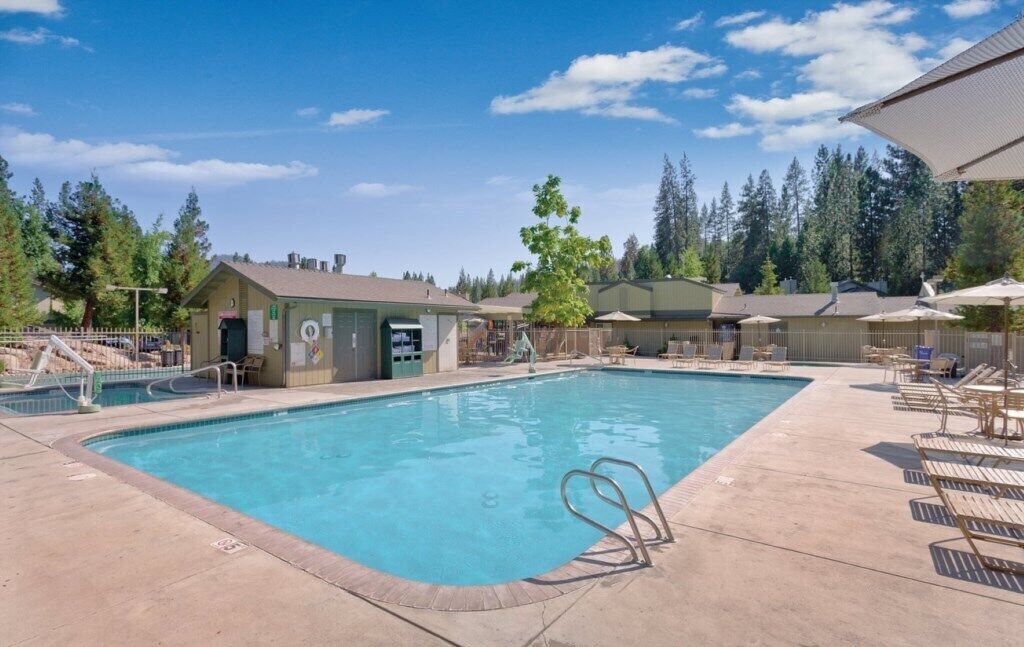 Une piscine avec des chaises longues et un petit bâtiment sur lequel est apposée une enseigne.
