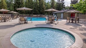 A hot tub surrounded by lounge chairs and umbrellas, with a pool and outdoor seating area in the background. - Bass Lake | Group Lake Getaway | Pool + Lake | 2BR (Bass Lake)