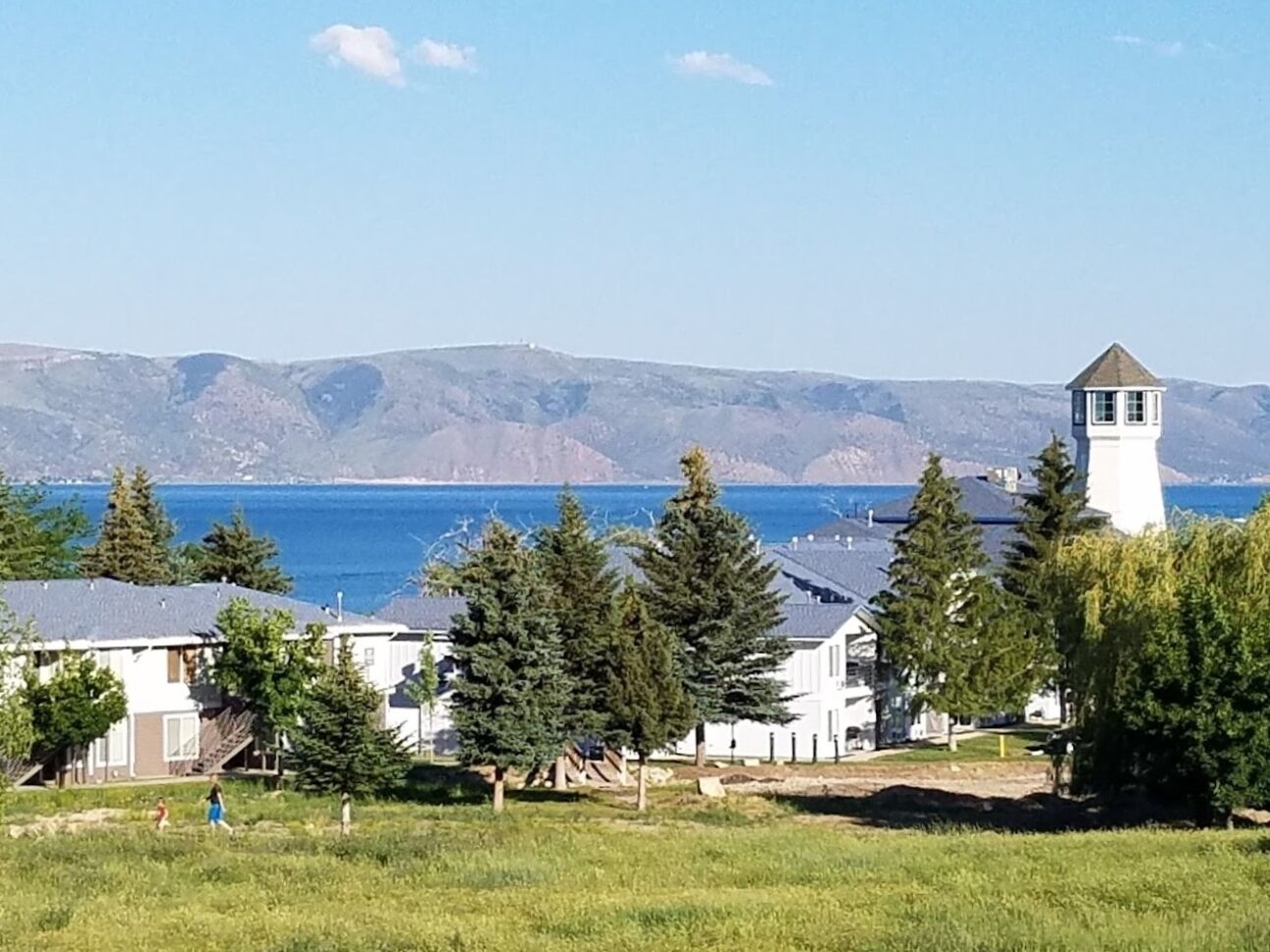 A coastal residential area with houses, a lighthouse, and a view of the sea.