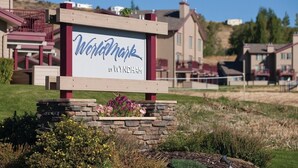 Schild für Wyndham by Wyndham in einer begrünten Anlage mit Häusern im Hintergrund.