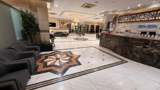 A hotel lobby with a marble floor, a reception desk, and seating areas.