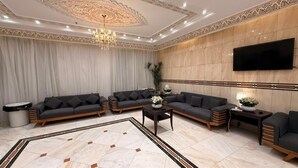 A spacious living room with a large sofa set, a coffee table, and a TV mounted on the wall.