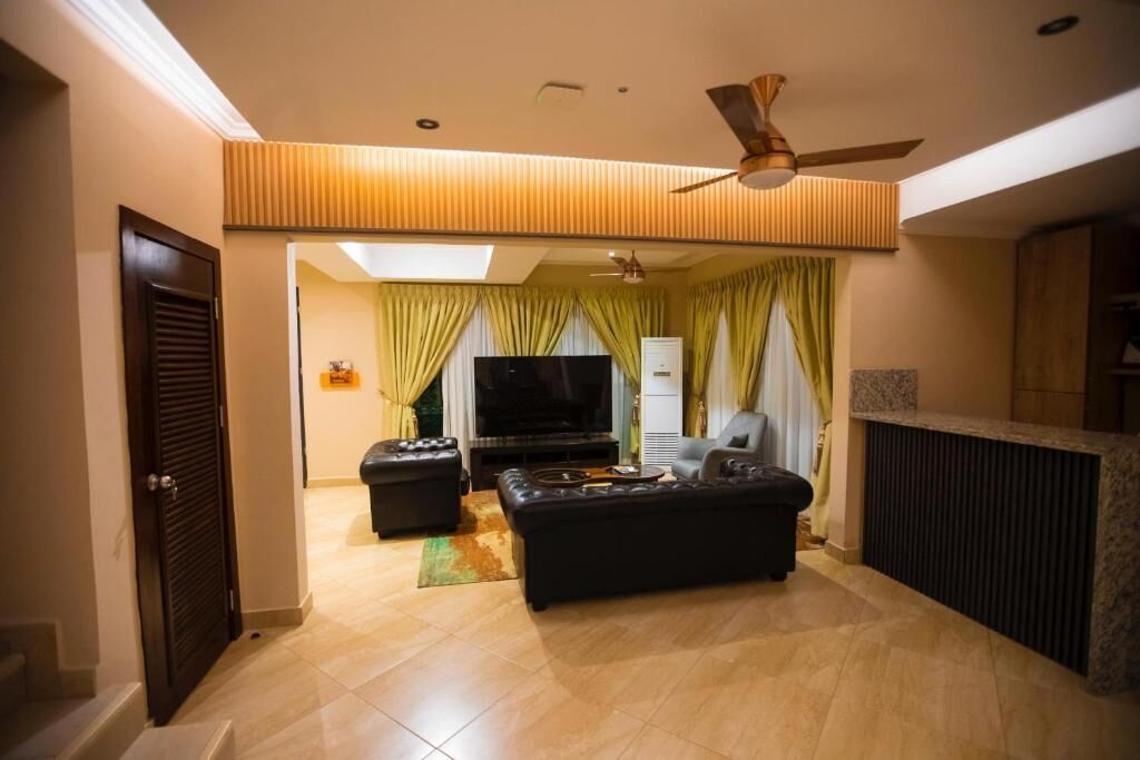 Ein Wohnzimmer mit einer Couch, einem Fernseher und einem Deckenventilator.
