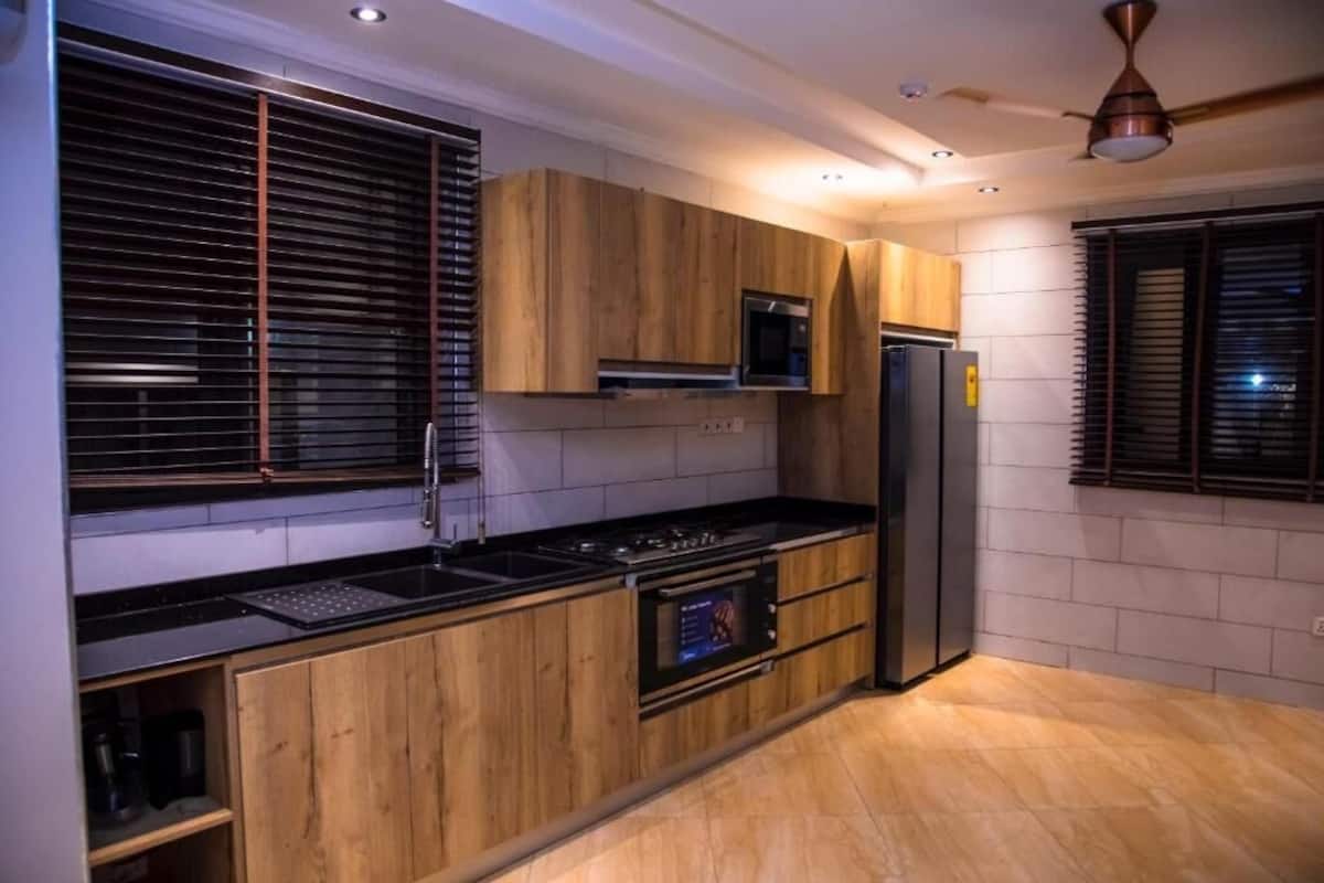 Una cocina moderna con armarios de madera, encimera negra, horno empotrado y refrigerador.