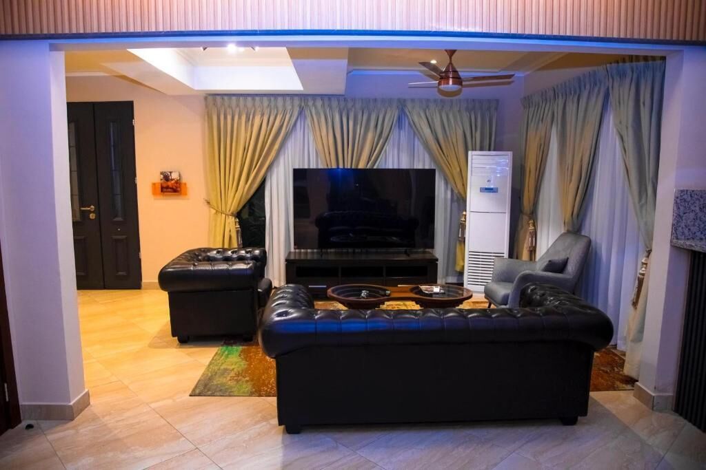 A living room with a black leather sofa, a television, and a ceiling fan.