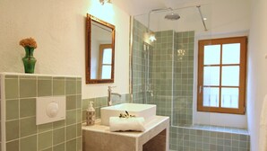 Ein Badezimmer mit Waschbecken, Spiegel, Dusche und einem Fenster.