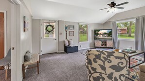 Ein Wohnzimmer mit Fernseher, Deckenventilator und Blick ins Freie.