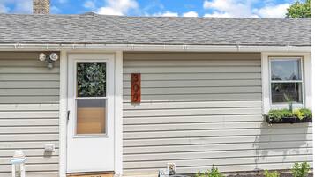 Une maison avec un panneau indiquant le numéro « 30 », une porte, une fenêtre et un petit jardin agrémenté de plantes.