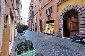 A cobblestone street lined with historic buildings, a motorcycle parked by the entrance, and a shop with a display window. - Luxury Historic Apartment near Piazza Navona (Roma)