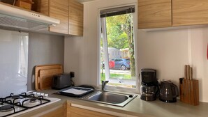 A compact kitchen with a gas stove, a toaster, a coffee maker, and a window with a view of the outside. - Bungalow in Lège-Cap-Ferret between pine forest, lake and ocean (Lège-Cap-Ferret)