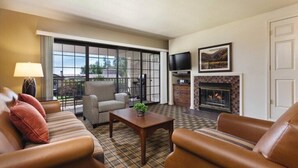 A living room with a sofa, armchair, and a fireplace.