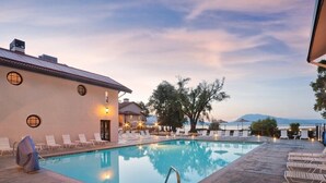 A pool area with lounge chairs and a building with a tiled roof.