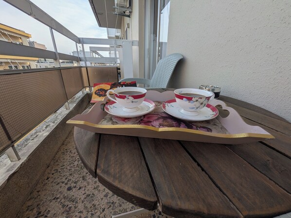Un balcon avec une table en bois, deux tasses de café et un plateau.