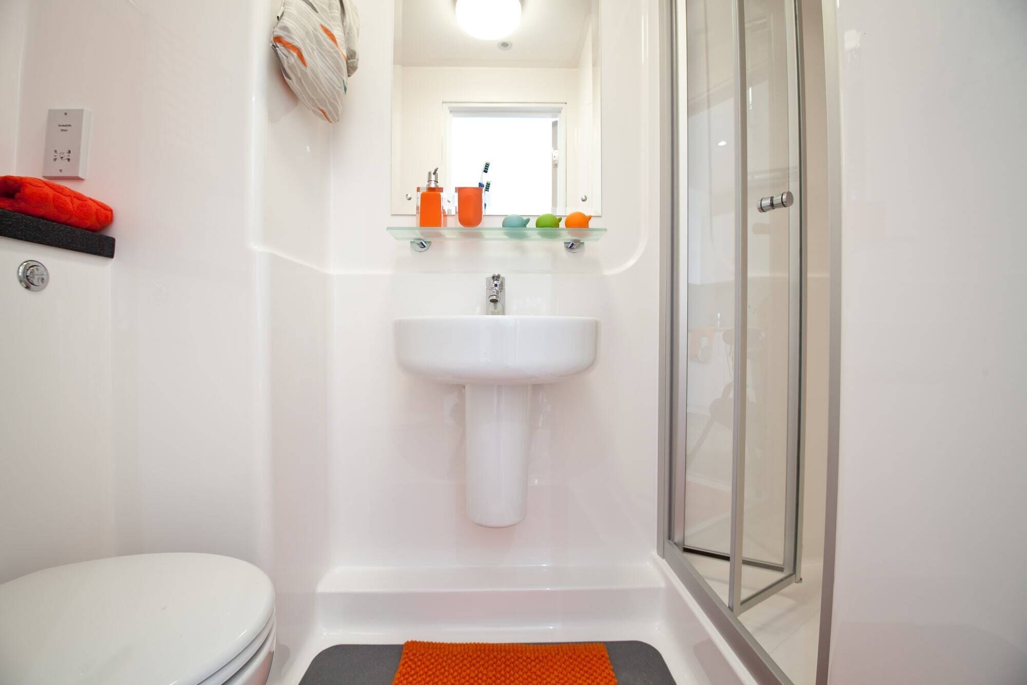 A bathroom with a white sink, a glass shower enclosure, and a toilet.