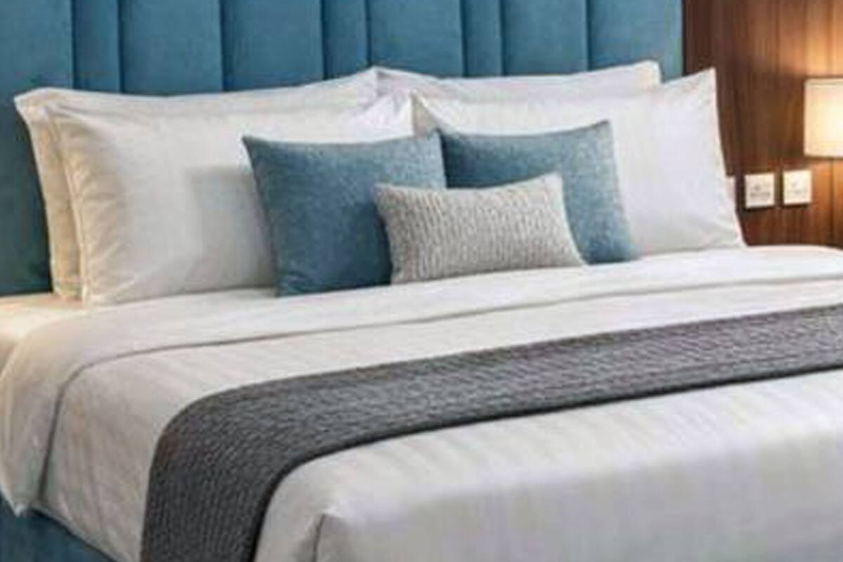 A bed with a blue upholstered headboard, white bedding, and multiple pillows.