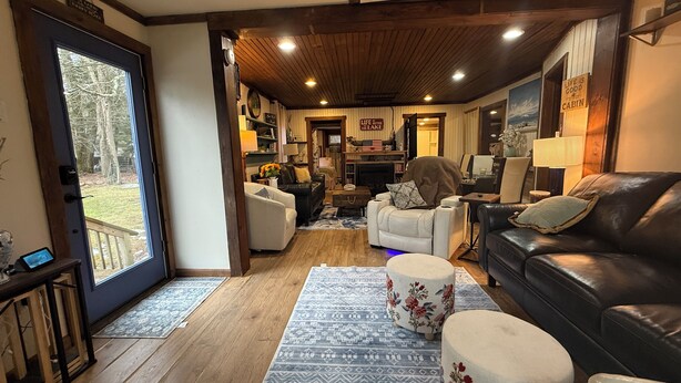 Un salon chaleureux avec une cheminée, des canapés en cuir et une grande fenêtre donnant sur une terrasse.