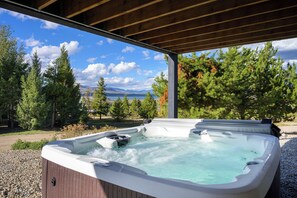 Un jacuzzi bajo una pérgola de madera con una vista panorámica de árboles y montañas.