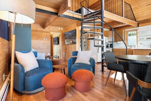 Ein gemütliches Blockhaus mit Holzwänden, einer Wendeltreppe, einem Essbereich und einer Küche.