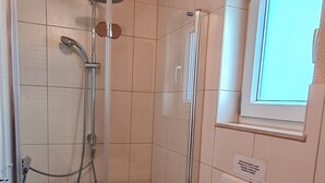 A bathroom with a shower, toilet, and a window. - Comfortably furnished vacation home with fireplace (Ilsenburg (Harz))