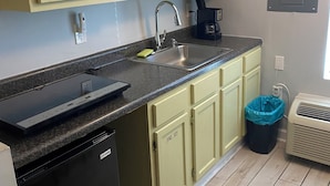 A kitchen with light green cabinets, a stainless steel sink, a microwave, a coffee maker, and a trash bin. - Condo in Gulf Shores with great location. Walk everywhere, 3mins from the beach. (Gulf Shores)