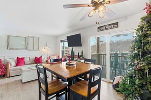 A cozy dining area with a wooden table and chairs, a ceiling fan, and a Christmas tree. - Ashley's Forgetaway For 4 (Branson)