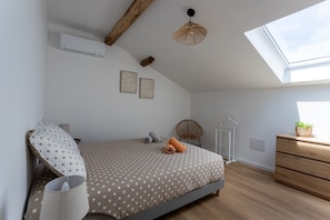 Une chambre à coucher avec un lit, un ventilateur de plafond, un puits de lumière, une commode et une plante.