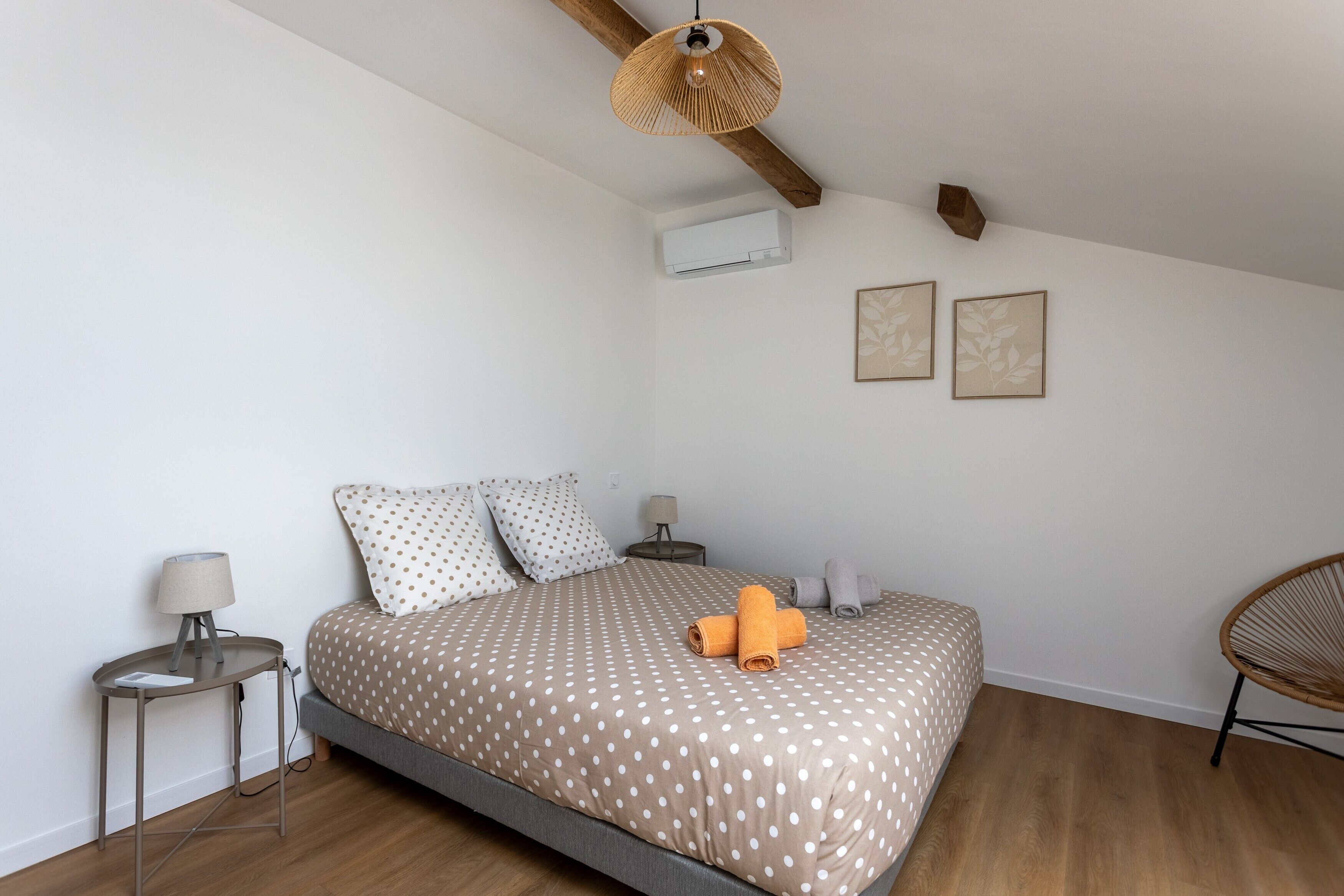 A bedroom with a bed, a bedside table, a lamp, a chair, and a ceiling fan.