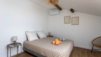 A bedroom with a bed, a bedside table, a lamp, a chair, and a ceiling fan.