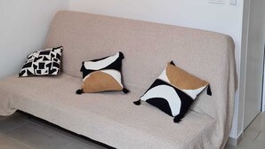 A living room with a beige sofa, three abstract wall art pieces, a black and white patterned pillow, and a modern staircase. - At sandra&fred your vacation in the dream of our cokon (Calvi)